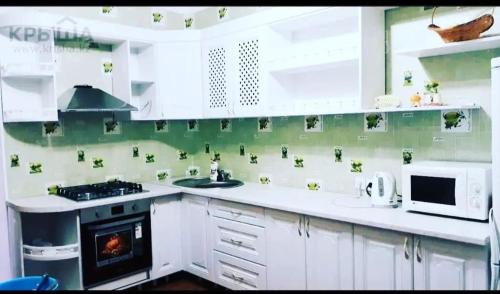 uma cozinha com um fogão, um lavatório e um micro-ondas em Гостевой дом Jasmine em Borovoye