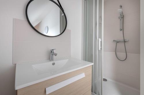 Un baño con un lavabo y un espejo en la pared. en Le Pouliguen - Maison lumineuse avec jardin, en Le Pouliguen