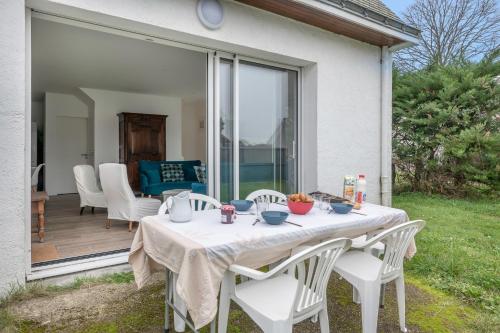 - une table avec des chaises blanches sur la terrasse dans l'établissement Le Pouliguen - Maison lumineuse avec jardin, au Pouliguen