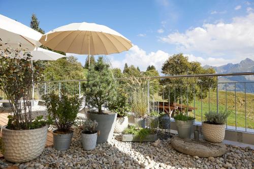 a patio with potted plants and an umbrella at Gantrisch Lodge Ottenleuebad in Guggisberg