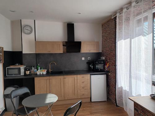 Il comprend une cuisine équipée d'un réfrigérateur blanc, d'une table et de chaises. dans l'établissement superbe appartement T2 proche de vulcania, à Pontaumur