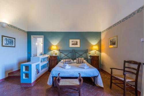 a bedroom with a blue bed and two chairs at Tenuta Mocajo in Guardistallo