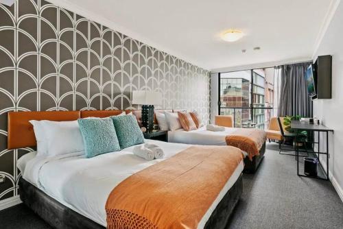 two beds in a hotel room with a wall at KozyGuru | Sydney CBD | Convenient City Studio in Sydney