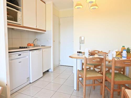 une cuisine avec des armoires blanches et une table et des chaises dans l'établissement Apartment L'Esquinade - F2 105 by Interhome, à Agay