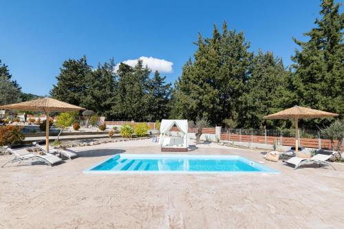 a swimming pool with chairs and umbrellas at Physis Luxury Villa in Archangelos