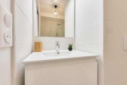 Un baño blanco con lavabo y espejo. en À 500m de la plage de la Jetée, appartement pour 4, en Andernos-les-Bains