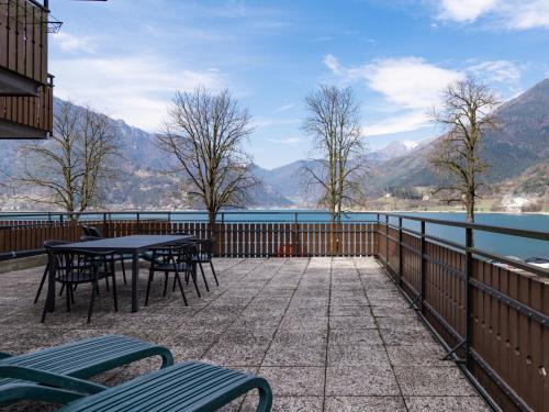 a patio with tables and chairs and a view of the water at Apartment Superior-1 by Interhome in Mezzolago