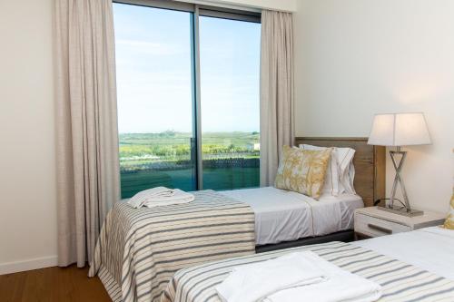 um quarto de hotel com duas camas e uma grande janela em Apartment Rising Sun By Dalma Portuguesa em Armação de Pêra