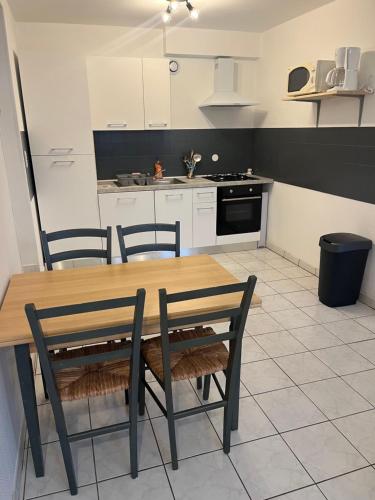 une cuisine avec une table et des chaises en bois dans l'établissement Joli appartement, à Cozes