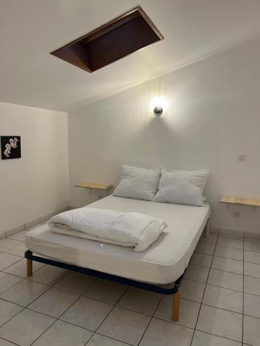 - un lit avec des draps et des oreillers blancs dans l'établissement Joli appartement, à Cozes
