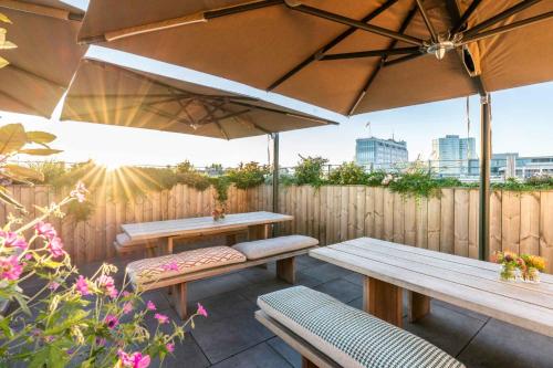 eine Terrasse mit 2 Picknicktischen und einem Sonnenschirm in der Unterkunft TORTUE HAMBURG - Schöner als die Fantasie in Hamburg