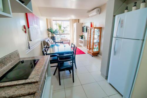a kitchen with a table and a white refrigerator at Flat Pietra in Florianópolis