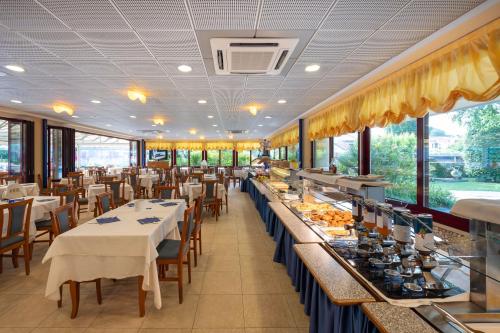 une salle à manger avec tables, chaises et fenêtres dans l'établissement Villaggio Planetarium Resort, à Bibione