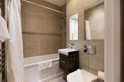 a bathroom with a sink and a toilet and a tub at The Harlesden Breakout - Glamorous 2BDR Flat in London