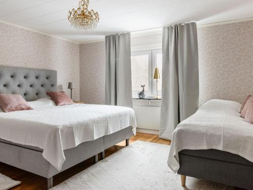 1 dormitorio con 2 camas y lámpara de araña en Holiday Home Skjutsmåla - B en Olofström