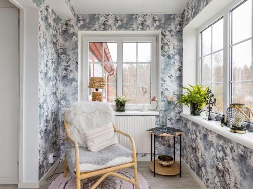 uma cadeira num quarto com papel de parede floral em Holiday Home Skjutsmåla - B em Olofström