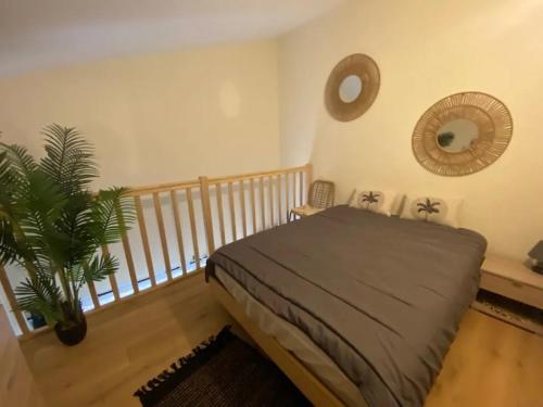 ein Schlafzimmer mit einem Bett und einer Pflanze darin in der Unterkunft Appartement au Parc de la Grange in Jard-sur-Mer