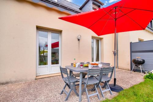 une table avec deux chaises et un parapluie rouge dans l'établissement Maison & jardin - 650 m de la plage 