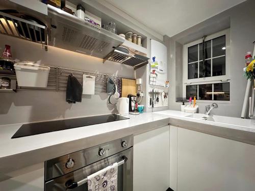 Wades Place E14 في لندن: مطبخ مع دواليب بيضاء ومغسلة