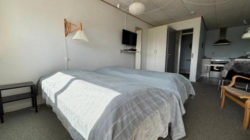 a bedroom with a bed and a desk and a kitchen at Søndervig Camping & Cottages in Søndervig