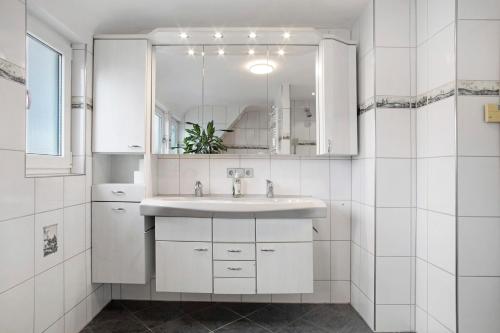 a white bathroom with a sink and a mirror at Zäh in Meckenbeuren