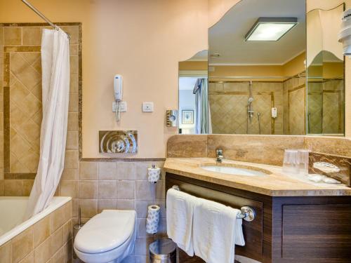 a bathroom with a sink and a tub and a toilet at Parc Hotel Germano Suites & Apartments in Bardolino