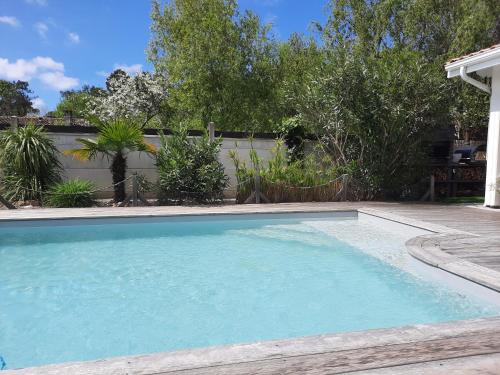 a swimming pool with blue water in a yard at Chambre d'hôtes La Perla du Teich, piscine chauffée in Le Teich