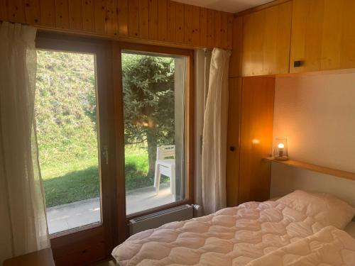 een slaapkamer met een bed en een groot raam bij Mont Rouge VIEW & CENTER apartments by Alpvision Résidences in Veysonnaz