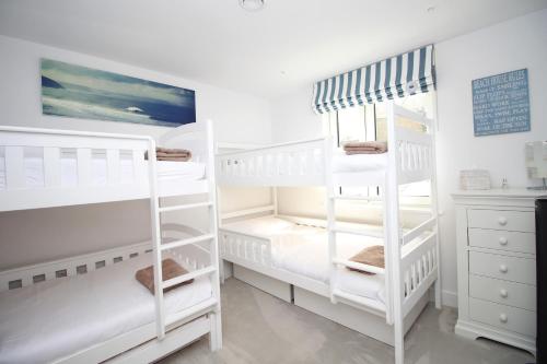 two white bunk beds in a white room at Coastal apartment sea views in Saint Merryn