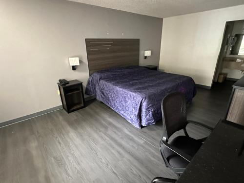 1 dormitorio con 1 cama y 1 silla en una habitación en ECONOMY INN, en Jonesboro