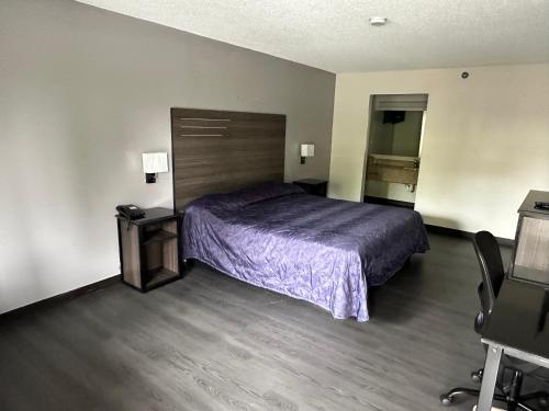 a bedroom with a bed with a purple bedspread at ECONOMY INN in Jonesboro