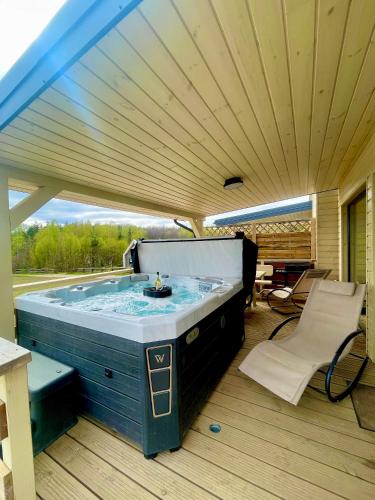 a jacuzzi tub in a room with a large window at Osada Skoczkowo komfortowe domki z prywatnymi wannami hot-tub nad jeziorem- sauna- balia- prywatny staw wędkarski in Podiazy