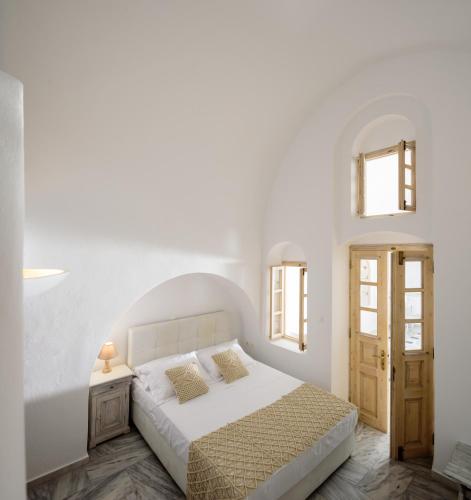 a white bedroom with a bed and two windows at MyBoZer Hotel Kallisto in Imerovigli