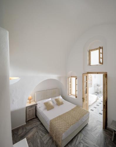 a white bedroom with a bed and a mirror at MyBoZer Hotel Kallisto in Imerovigli