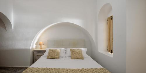 a bedroom with a white bed with an arched ceiling at MyBoZer Hotel Kallisto in Imerovigli