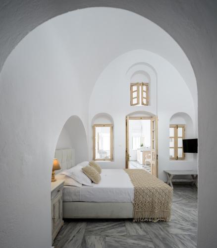 a white bedroom with a bed and two mirrors at MyBoZer Hotel Kallisto in Imerovigli