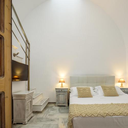 a bedroom with a bed and a flat screen tv at MyBoZer Hotel Kallisto in Imerovigli