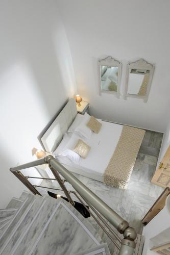 a bed in a white room with two mirrors at MyBoZer Hotel Kallisto in Imerovigli