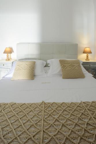 a large white bed with pillows and two lamps at MyBoZer Hotel Kallisto in Imerovigli