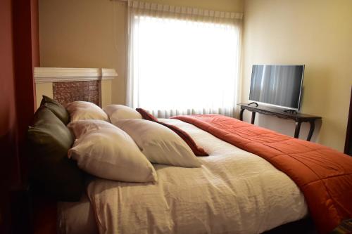 a bedroom with a bed with pillows and a television at Raven La Paz in La Paz