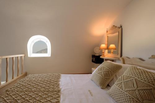 a bedroom with a bed and an arched window at MyBoZer Hotel Kallisto in Imerovigli