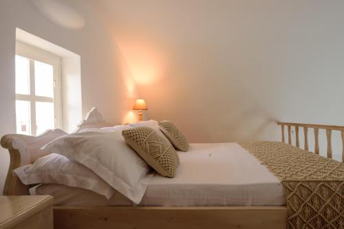 a bedroom with a bed with white sheets and a window at MyBoZer Hotel Kallisto in Imerovigli
