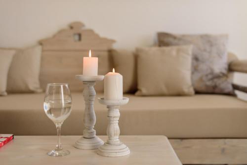 two candles and a wine glass on a table at MyBoZer Hotel Kallisto in Imerovigli