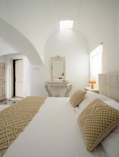 a white bedroom with a large bed and a mirror at MyBoZer Hotel Kallisto in Imerovigli