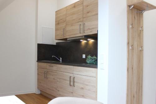 a kitchen with wooden cabinets and a sink at Hotel am Wittelsbacher Markt by greenpartment in Langquaid