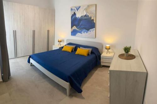 una camera da letto con letto con lenzuola blu e cuscini gialli di Yellow Hill Penthouse a Żebbuġ