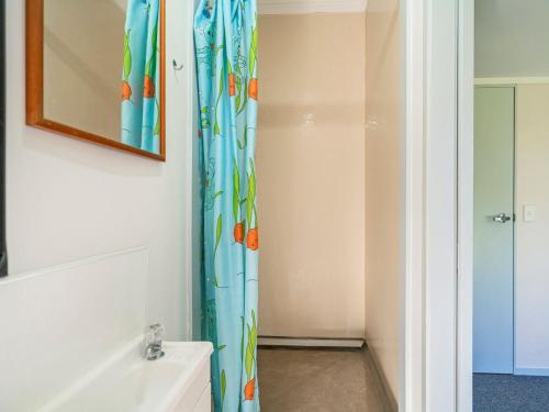 La salle de bains est pourvue d'un rideau de douche avec des poissons. dans l'établissement Seashells Bach - Whangamatā Holiday Home, à Whangamata