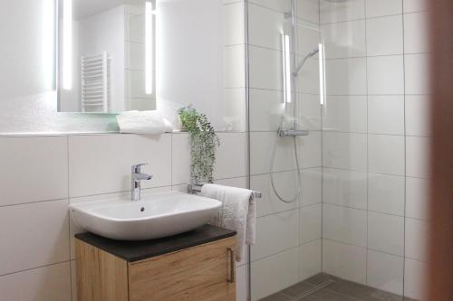 a white bathroom with a sink and a shower at Hotel am Wittelsbacher Markt by greenpartment in Langquaid