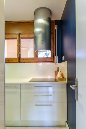 a kitchen with white cabinets and a silver stove at Flateli La Fosca in Palamós