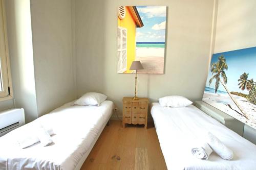 - 2 lits dans une chambre avec une photo de la plage dans l'établissement FOUR BEDROOMS/SEA VIEW, à Cannes